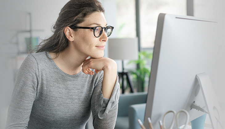 Discover the Remote Work Report 2022 Woman with glasses looking at a monitor